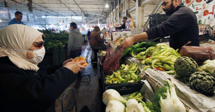 Femme achetant des légumes frais dans un marché algérien.