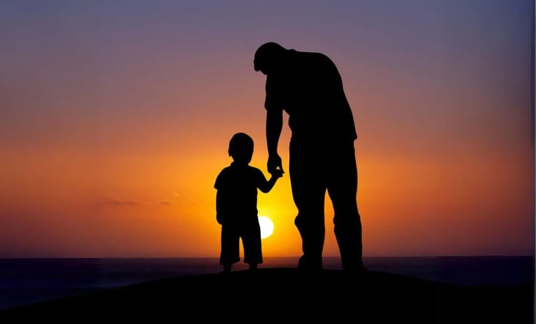 Silhouette d'un père et son fils tenant la main au coucher du soleil.