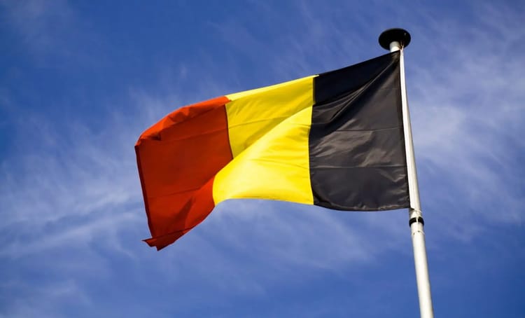 Immigration : Ultime porte de sortie pour la Belgique Drapeau national belge au vent contre un ciel bleu clair.