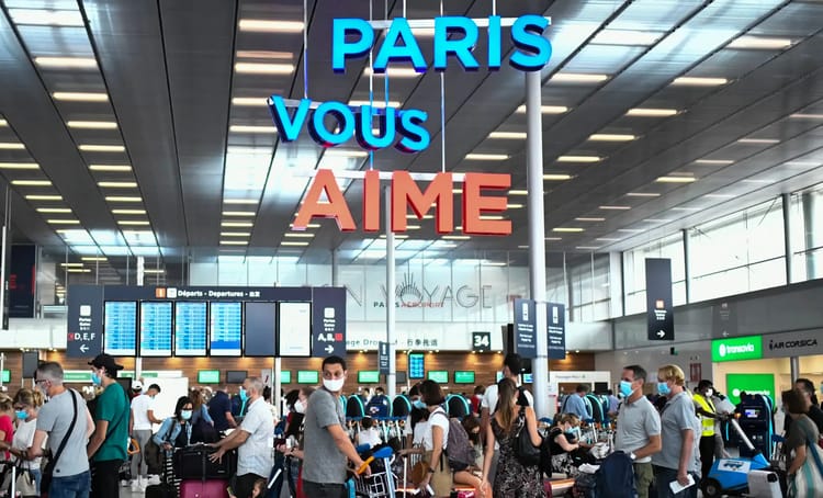 Voyageurs à l'aéroport de Paris avec affichages et comptoirs.