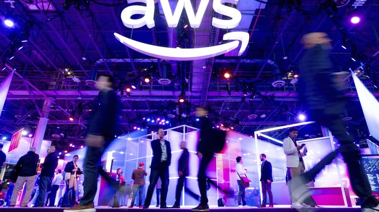 Amazon : Eric Sheridan (Goldman Sachs) et Thomas Champion (Piper Sandler) Voient Juste - Prévisions pour 2024 Participants lors d'un événement AWS avec le logo Amazon en arrière-plan.