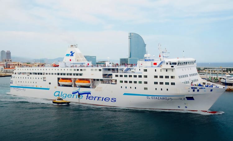 Ferry Algérie Ferries naviguant au port avec la ville en arrière-plan.