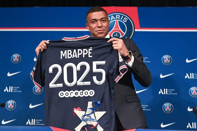 Kylian Mbappé tenant un maillot du PSG 2025 lors d'une conférence de presse.