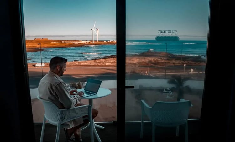 Aubaine à saisir! L'Italie envisage un visa spécial, pour booster son économie Homme travaillant sur un ordinateur avec vue sur la mer et un parc éolien.