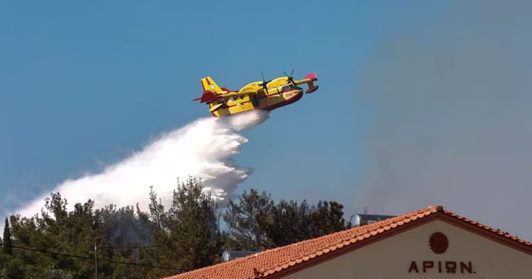 Avion bombardier pulvérisant de l'eau lors d'une lutte contre un incendie de forêt.