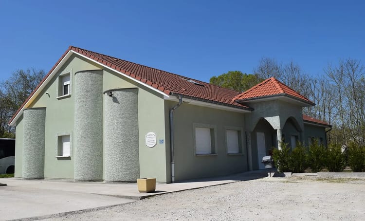 Maison moderne avec façade verte et toit en tuiles rouges.