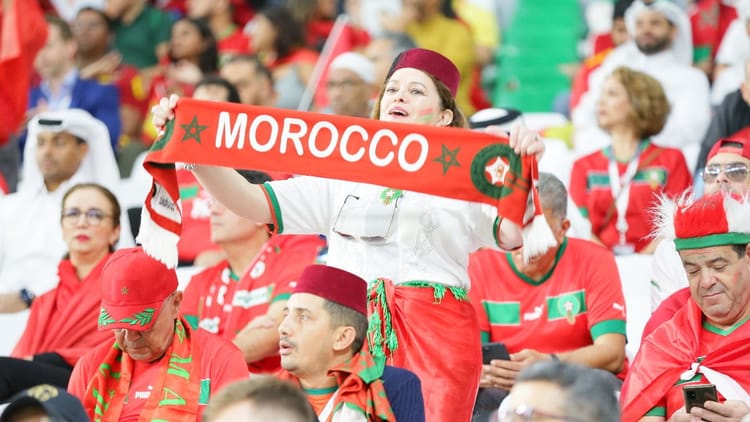 Supporters marocains en tenue traditionnelle et avec drapeau lors d'un match de football.