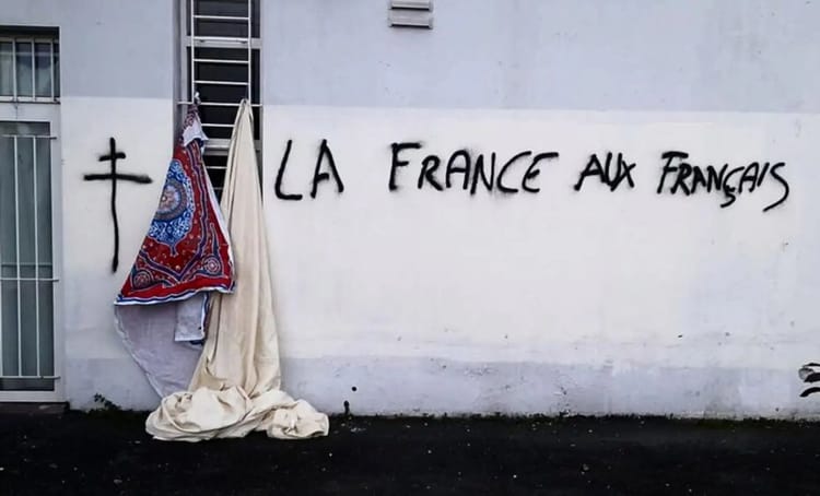 Graffiti avec texte "La France aux Français" sur un mur blanc.