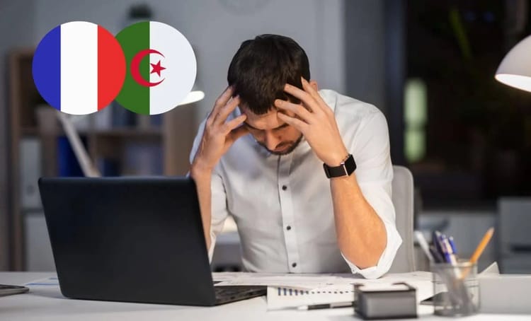 Homme stressé au bureau avec drapeaux France et Algérie.