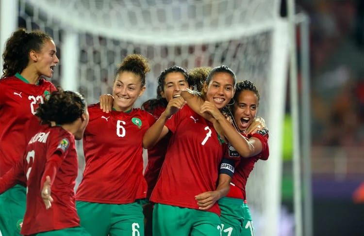 Joueuses marocaines de football célébrant un but lors d'un match.