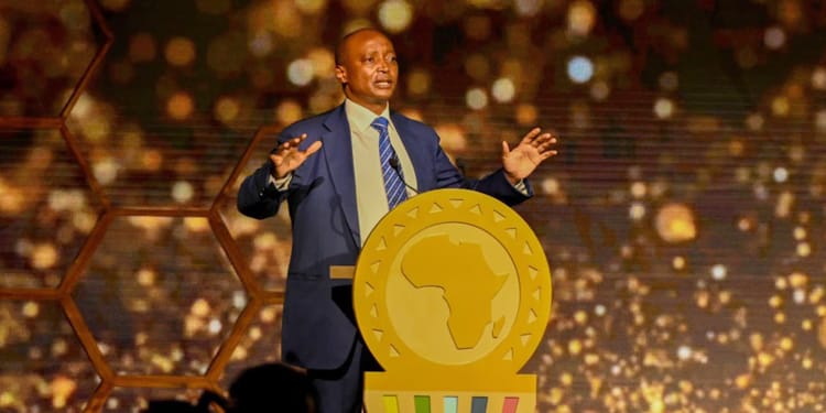 Homme en costume lors d'une conférence sur la CAN 2025 au Maroc.