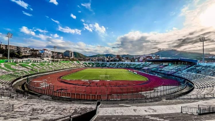 Stade de football en Algérie avec piste d'athlétisme et tribunes.