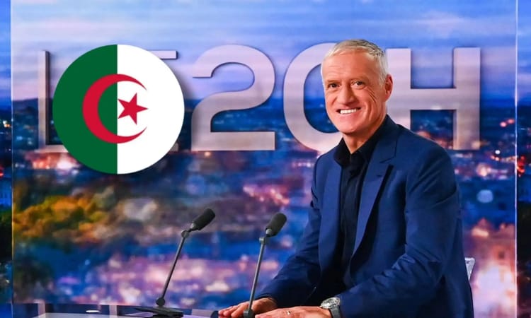 Didier Deschamps souriant à une conférence avec drapeau algérien en arrière-plan.
