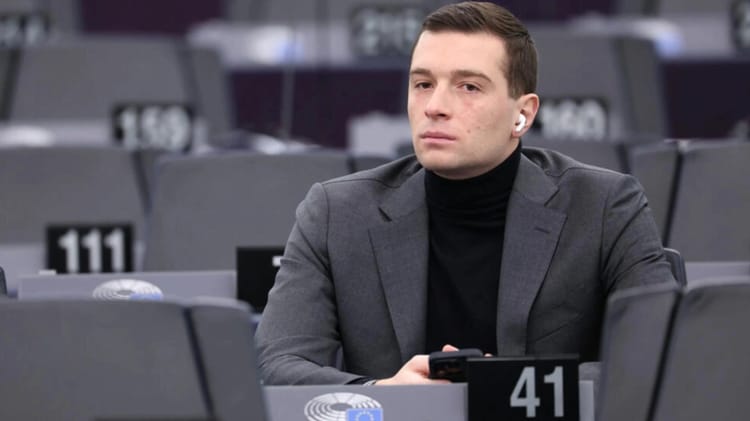 Jordan Bardella assis seul dans une salle de réunion du Parlement européen.