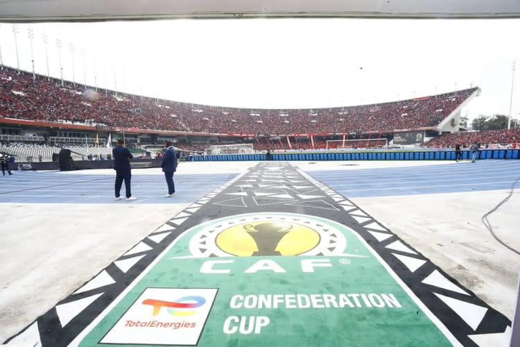 C'est terminé! La CAF décide enfin du sort de l'USM Alger Vue du terrain de football avec logo de la CAF et stade rempli en arrière-plan.