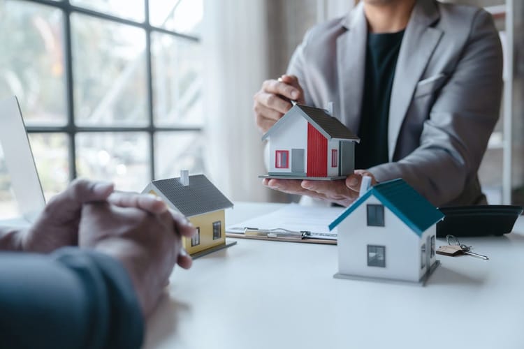 Agent immobilier montrant une maquette de maison à un client.