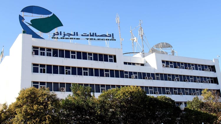 C'est fait ! Algérie Télécom sponsor officiel de l'USMK pour 2024-2025 Bâtiment d'Algérie Télécom avec logo et antennes.