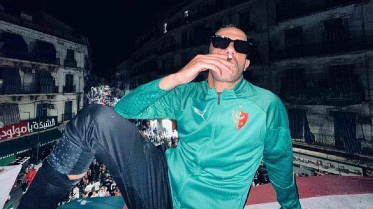Le MCA sème la panique en Angleterre! Une célébration du club algérien tourne au vinaigre Supporter du club algérien MCA portant maillot vert et lunettes de soleil.