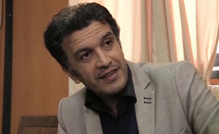 Fethi Ghares en discussion dans un cadre intérieur.