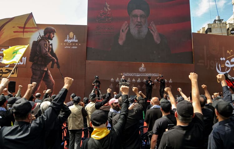 Manifestation populaire avec discours de Nasrallah sur grand écran.
