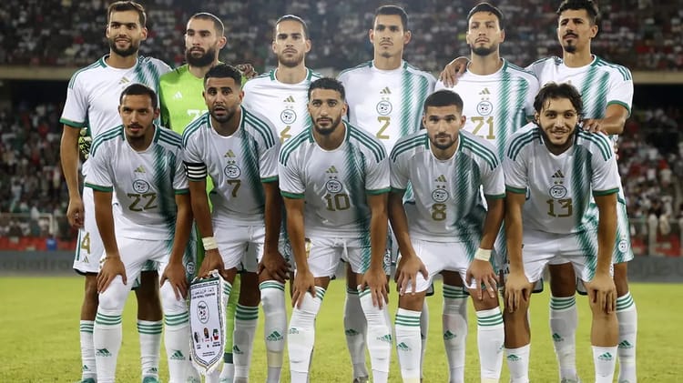 Groupe de joueurs de football algériens en tenue blanche sur le terrain.