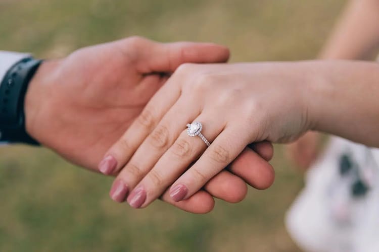 Main d'une jeune fille avec bague de fiançailles, symbole d'engagement.