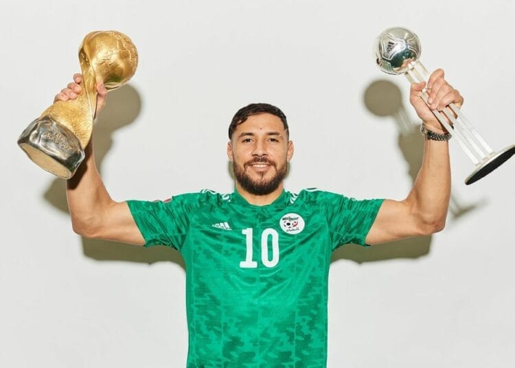 Youcef Belaïli tenant deux trophées, célébrant sa victoire.