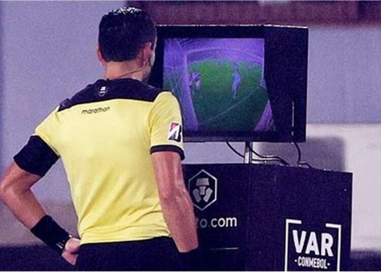 Arbitre de football regardant un écran de VAR lors d'un match.