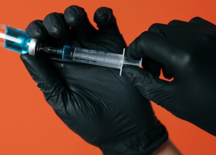 Vaccination Contre la Grippe : Le Ministère de la Santé fait une annonce ultra importante Main en gants noirs avec une seringue prête à être injectée.
