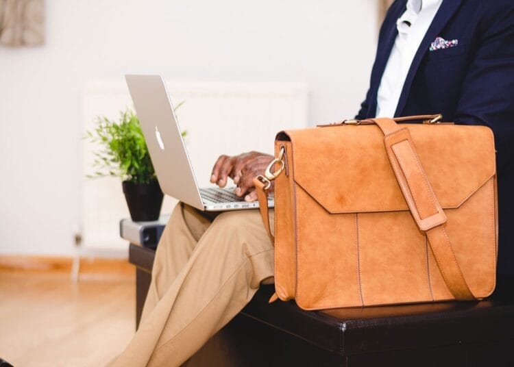 Homme d'affaires utilisant un ordinateur portable avec un sac en cuir marron.