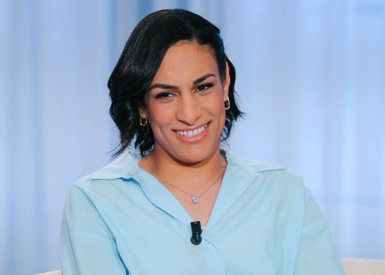 Imane Khelif souriante, vêtue élégamment, dans un décor moderne.