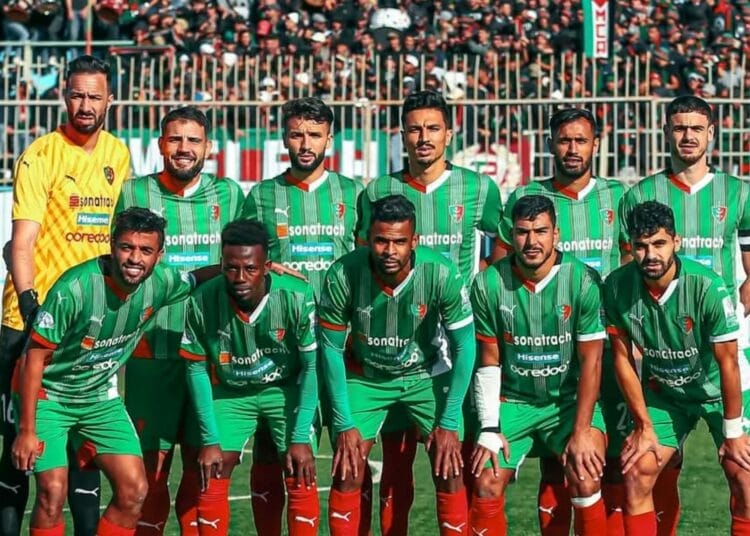 Groupe de joueurs Mouloudia en uniforme vert sur le terrain de football.