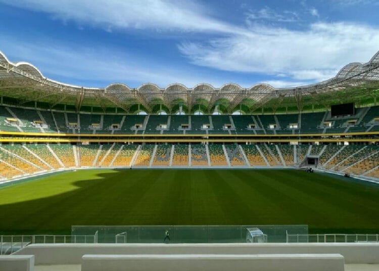 Stade de football vide avec ciel bleu et nuages.