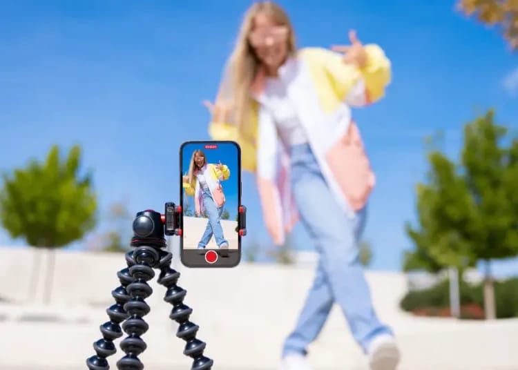 Jeune femme prenant une vidéo TikTok en extérieur avec un smartphone.