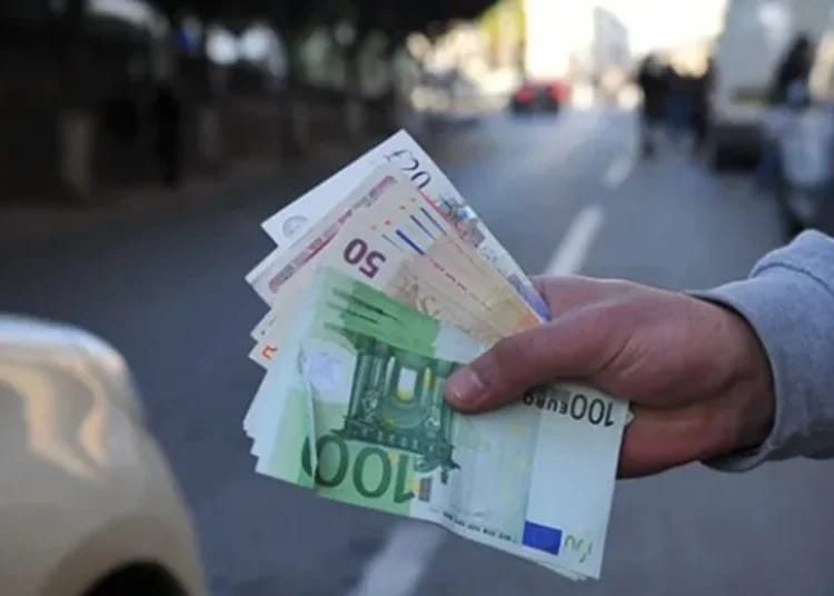 Taux de change en Algérie : La valeur de 100€ face au DZD sur le marché noir ce 2 novembre 2024 Main tenant des billets de banque en euros sur une rue urbaine.