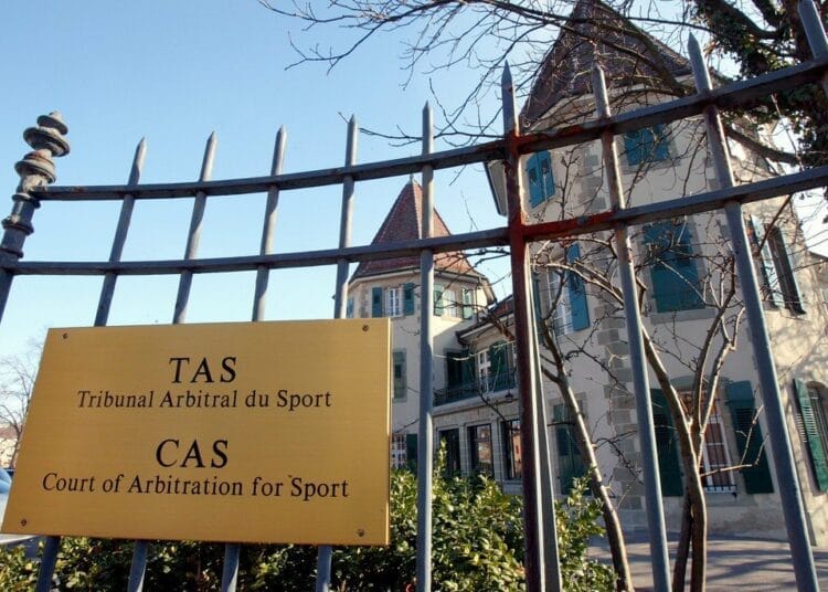 Panneau TAS Tribunal Arbitrale du Sport devant une maison ancienne.
