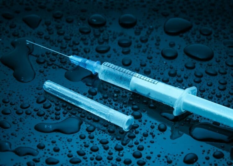 Seringue et ampoule sur surface mouillée, concept médical.