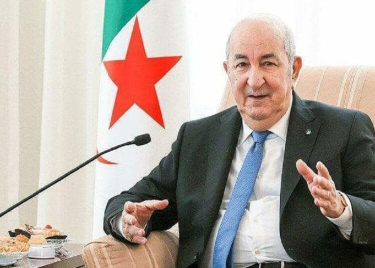 Président Tebboune en réunion avec drapeau algérien en arrière-plan.