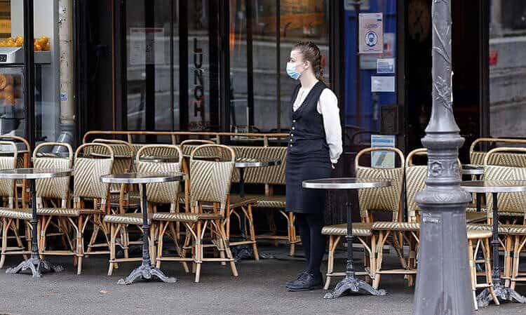 Serveuse portant un masque dans un restaurant de Lyon avec des tables vides.