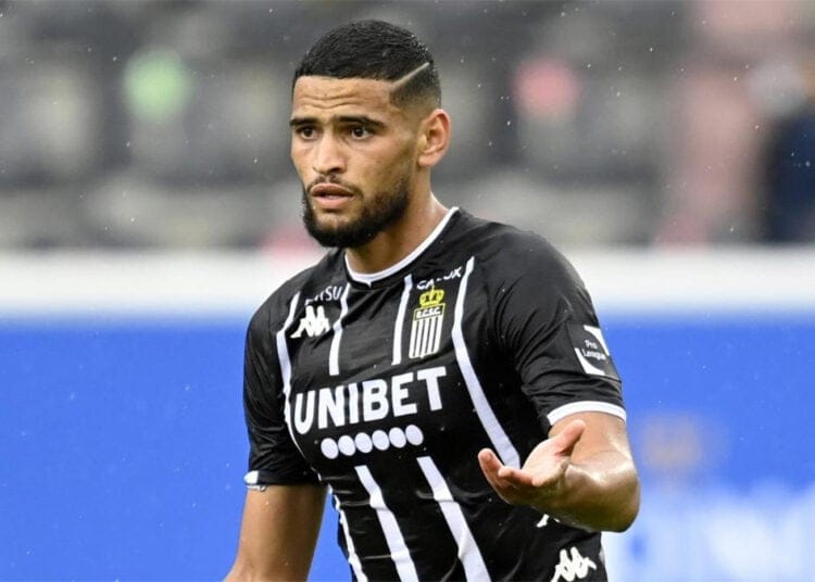 Footballeur algérien portant un maillot noir et blanc sur le terrain.