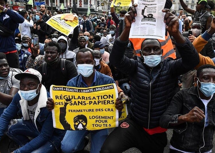 Manifestants avec pancartes pour la régularisation des sans-papiers en France.