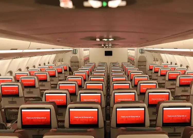 Intérieur d'un avion avec sièges et écrans de divertissement modernes.