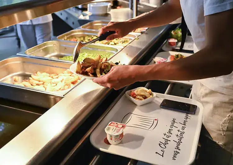 Repas étudiant à 1 € : ce qui change dès maintenant en France Étudiant servant un repas dans une cafétéria universitaire en France.