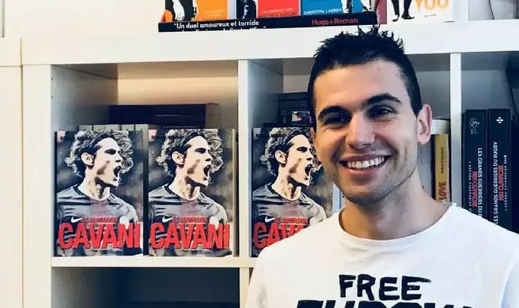 Romain Molina visé au Maroc pour ses liens avec l’Algérie Romain Molina souriant devant une bibliothèque avec des livres sur Cavani.