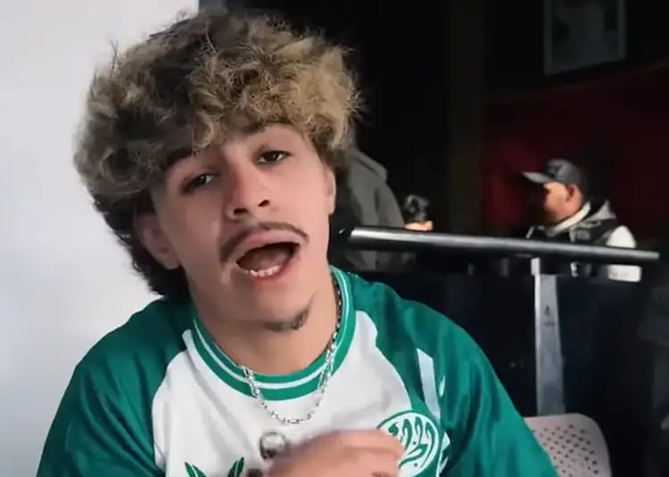 Jeune homme parlant avec expression expressive, cheveux bouclés, en intérieur.
