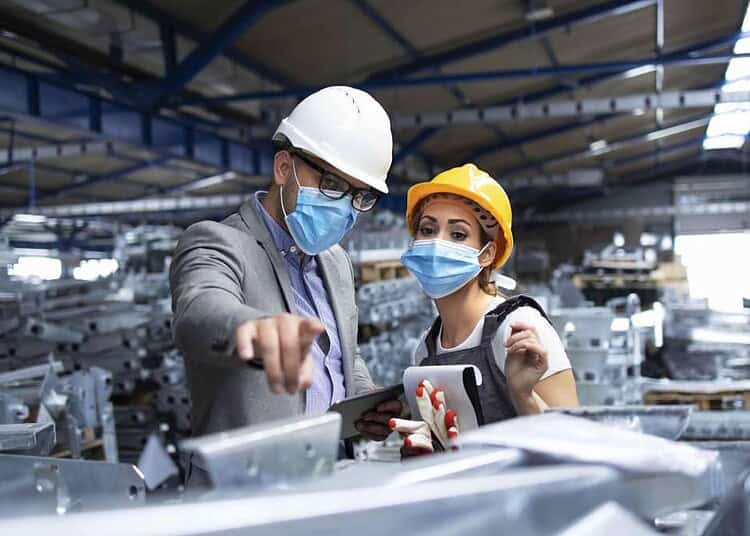 Italie 2026 : 43 300 Nouveaux Emplois pour Étrangers Deux travailleurs portant casque et masque dans une usine moderne.