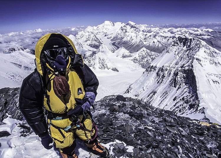 Alpiniste en haute altitude avec vue sur l'Everest enneigé.