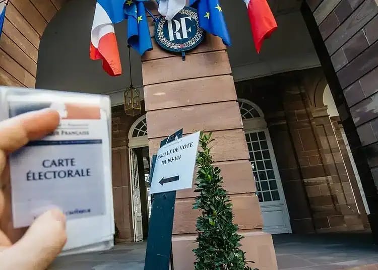 Voter avec la carte électorale devant un bâtiment officiel en France.