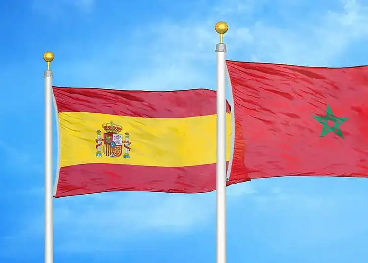 Le Maroc : une menace grandissante pour l'Espagne ? Drapeaux de l'Espagne et du Maroc flottant dans le ciel bleu.