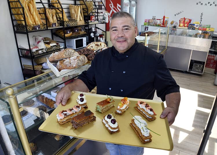 Akim Boughazi tenant un plateau de pâtisseries dans une boulangerie.